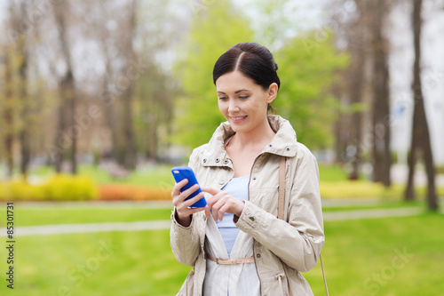 smiling woman calling on smartphone in park