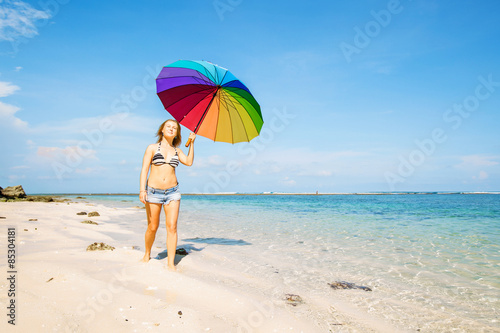 Young woman in blue shorts with colourful rainbow umbrella