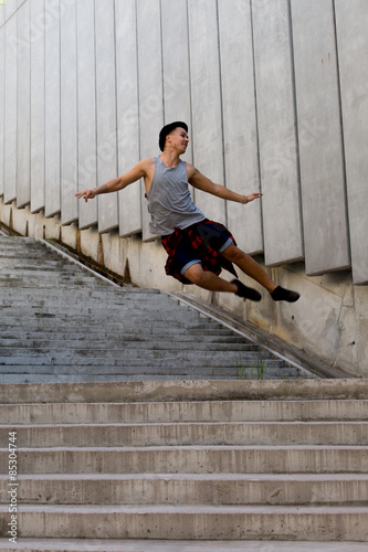 cool young and handsome caucasian brunette hipster skater guy wearing a hat posing smiling and having fun outside during amazing summer day in the city with