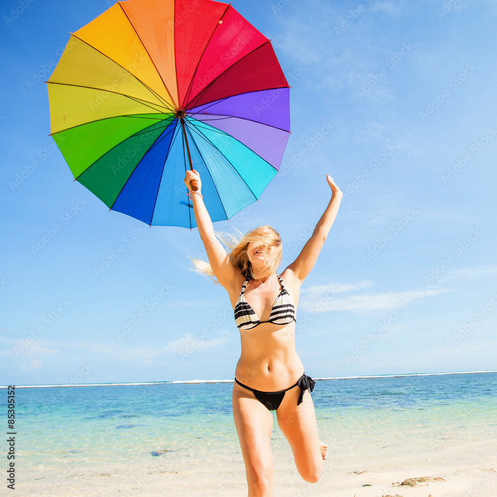 Young skinny girl in blue shorts with colourful rainbow umbrella