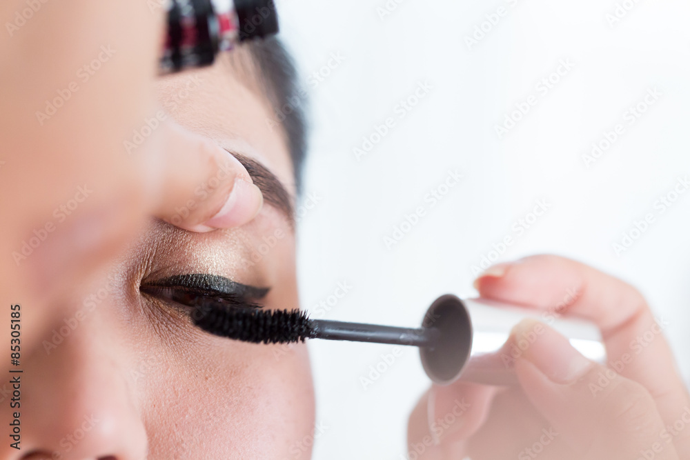 makeup artist used mascara brush with beautiful woman eyelashes