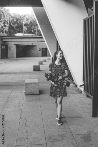 cool young and beautiful caucasian blonde teenager hipster skater girl with long gorgeous hair is posing smiling and having fun outside while skating with her cute little skate summer day