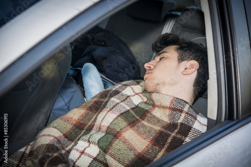 Young handosme man sleeping in his car