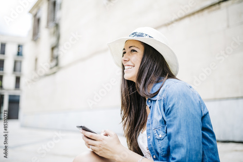 Young smiling woman text messaging on mobile phone