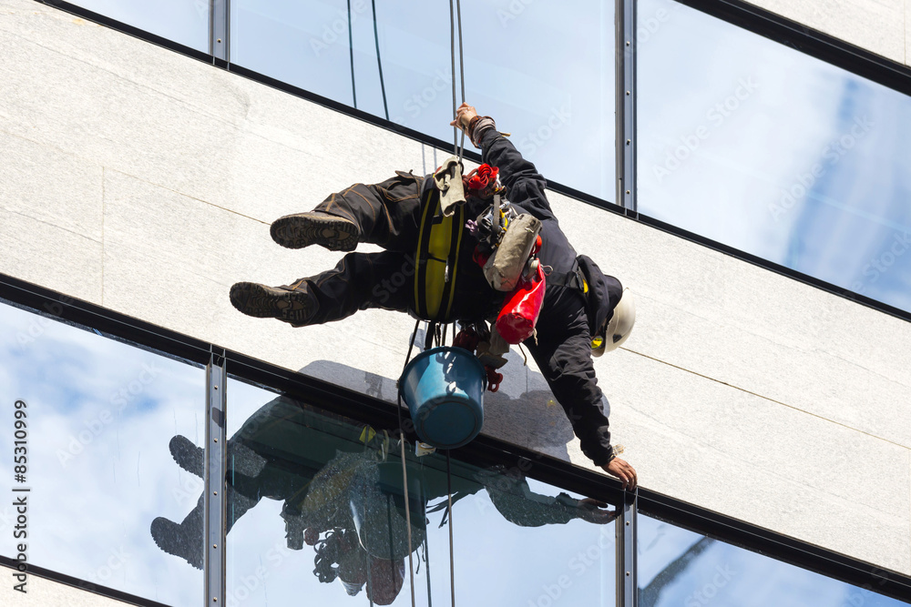 industrial climber working on the office building - cleaning the windows