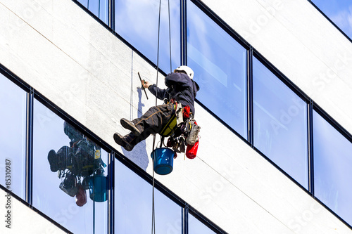 industrial climber working on the office building - cleaning the windows