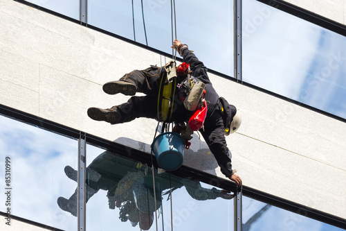 industrial climber working on the office building - cleaning the windows