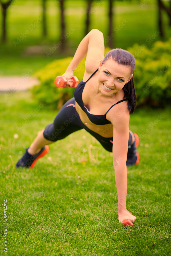 Female fitness instructor exercising with small weights in green Female fitness instructor exercising with small weights in green