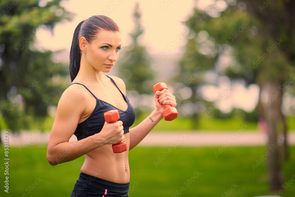 Female fitness instructor exercising with small weights in green Female fitness instructor exercising with small weights in green
