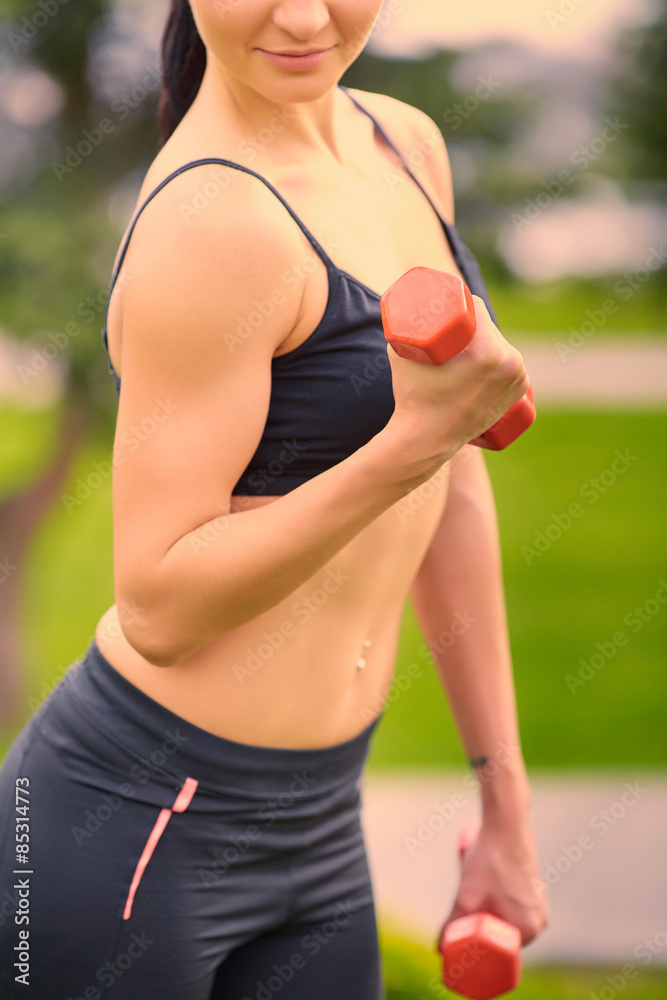 Fototapeta premium Female fitness instructor exercising with small weights in green