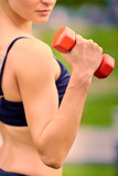 Female fitness instructor exercising with small weights in green