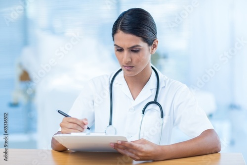 Beautiful doctor holding clipboard with file