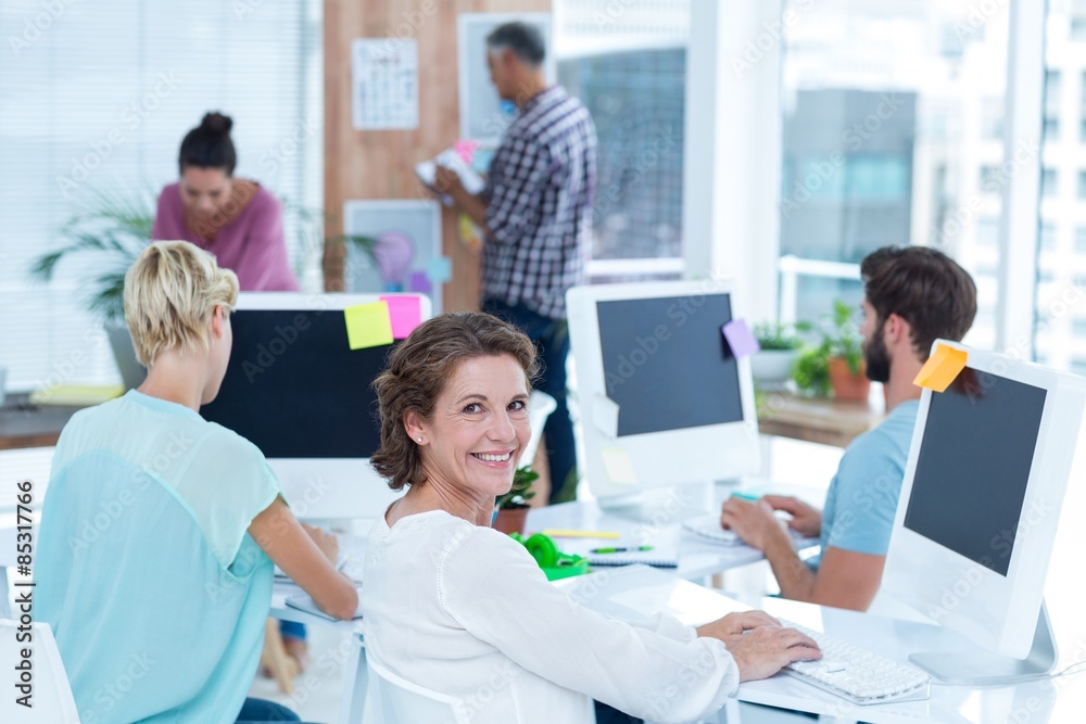 Smiling young woman working with her colleague at desk Smiling young woman working with her colleague at desk