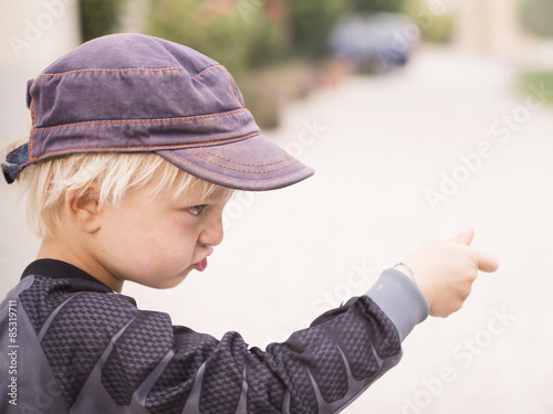 Blond boy playing, making shooting gesture photo