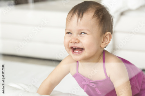 Laughing baby girl crawling on the floor photo