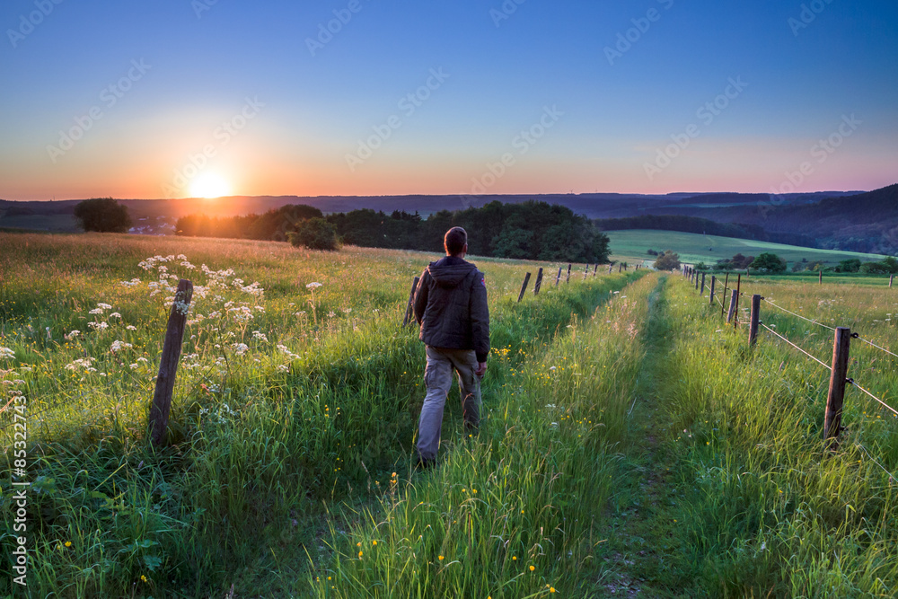 Man walking along Path Towards Sunset