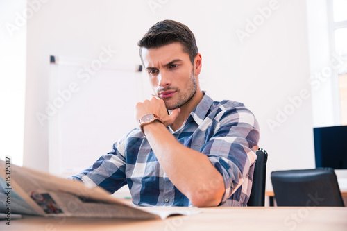 Casual businessman reading newspaper in office