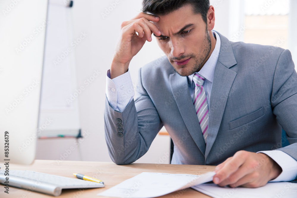 Handsome businessman sitting at the table in office Handsome businessman sitting at the table in office