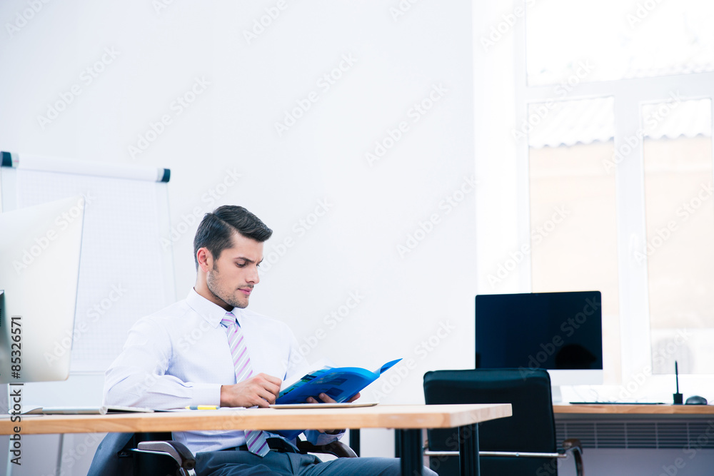 Businessman sitting at the table and reading document