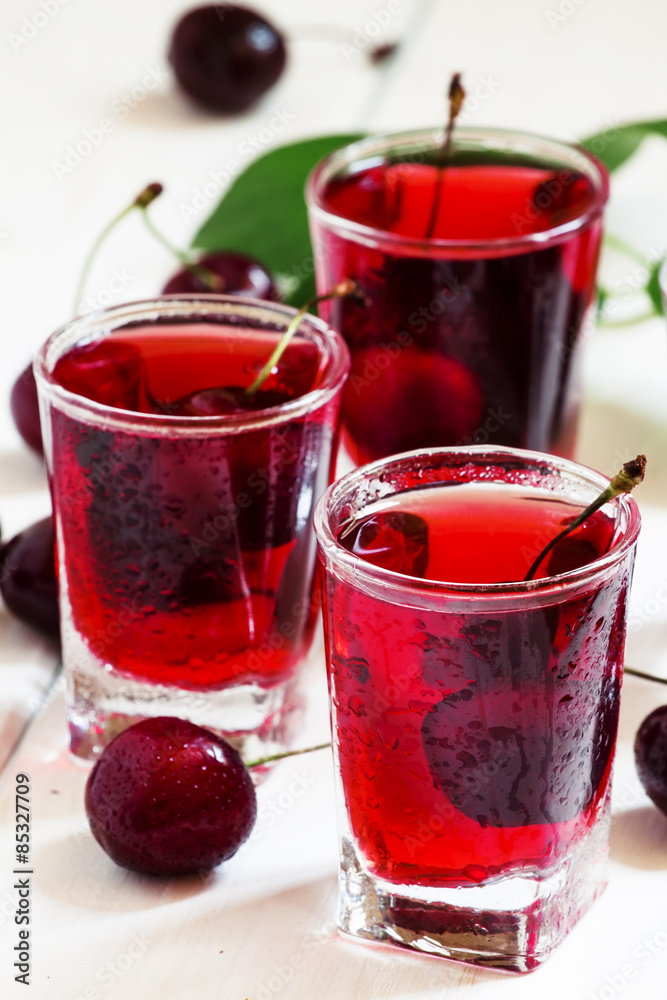 Homemade cherry liqueur and fresh cherries, selective focus Homemade cherry liqueur and fresh cherries, selective focus