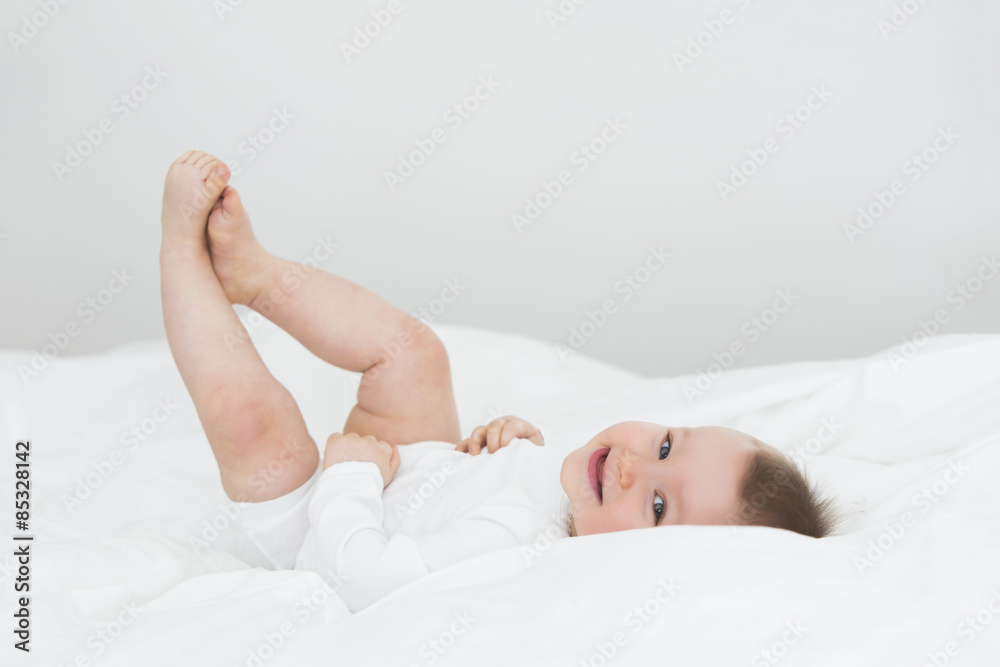 Smiling baby girl lying on bed Smiling baby girl lying on bed