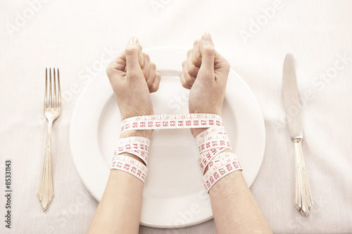 Woman in front of empty plate bound with tape measure