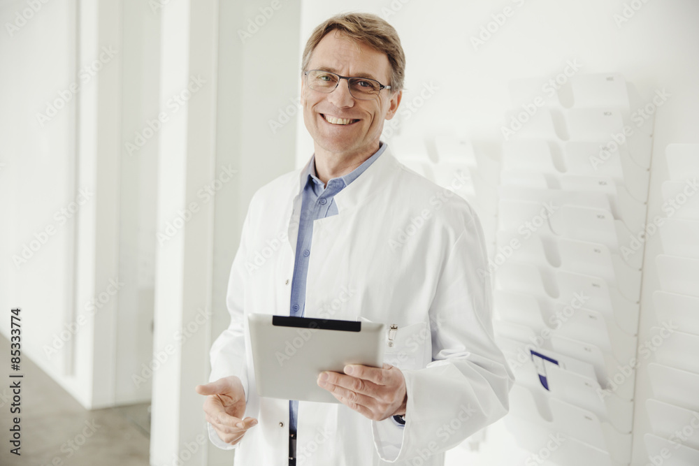 Smiling mature man in lab coat holding digital tablet Smiling mature man in lab coat holding digital tablet