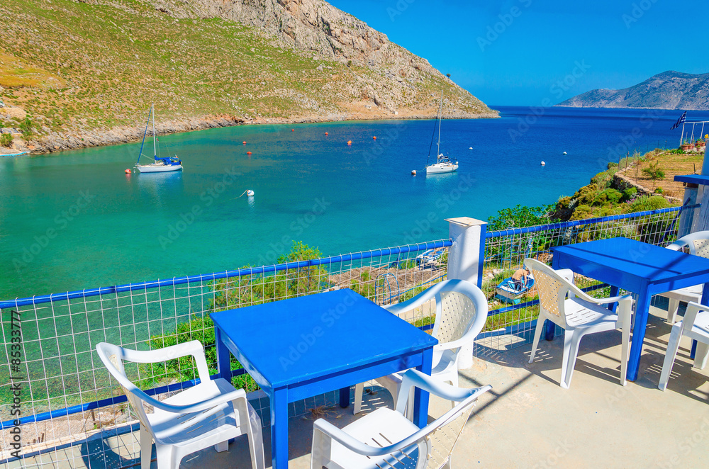Blue wooden tables and chairs in bay, Greek Island