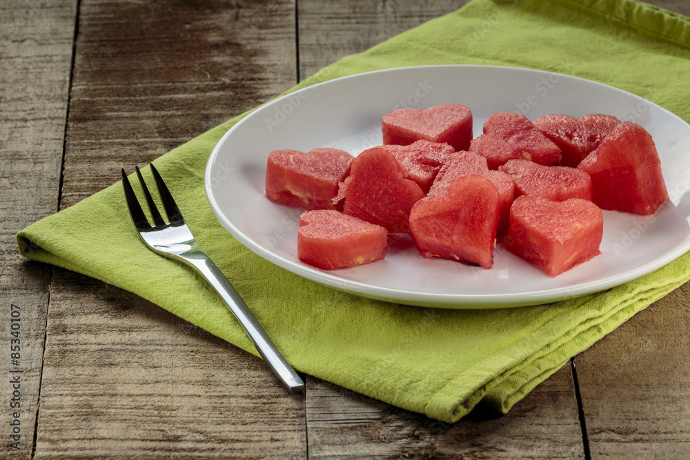 Slices of watermelon in the heart shape on vintage wooden table Slices of watermelon in the heart shape on vintage wooden table
