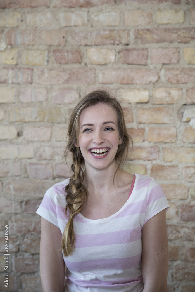 Portrait of laughing young woman in front of brick wall Portrait of laughing young woman in front of brick wall