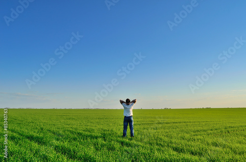 Young man on the summer green field under clear skies