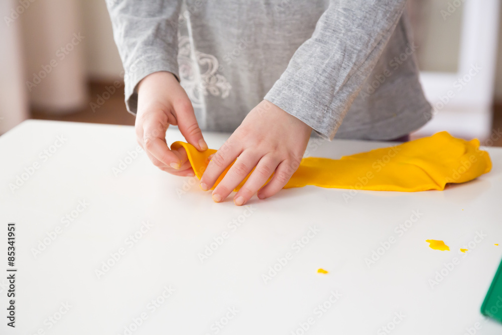 Little girl playing with yellow modeling clay Little girl playing with yellow modeling clay