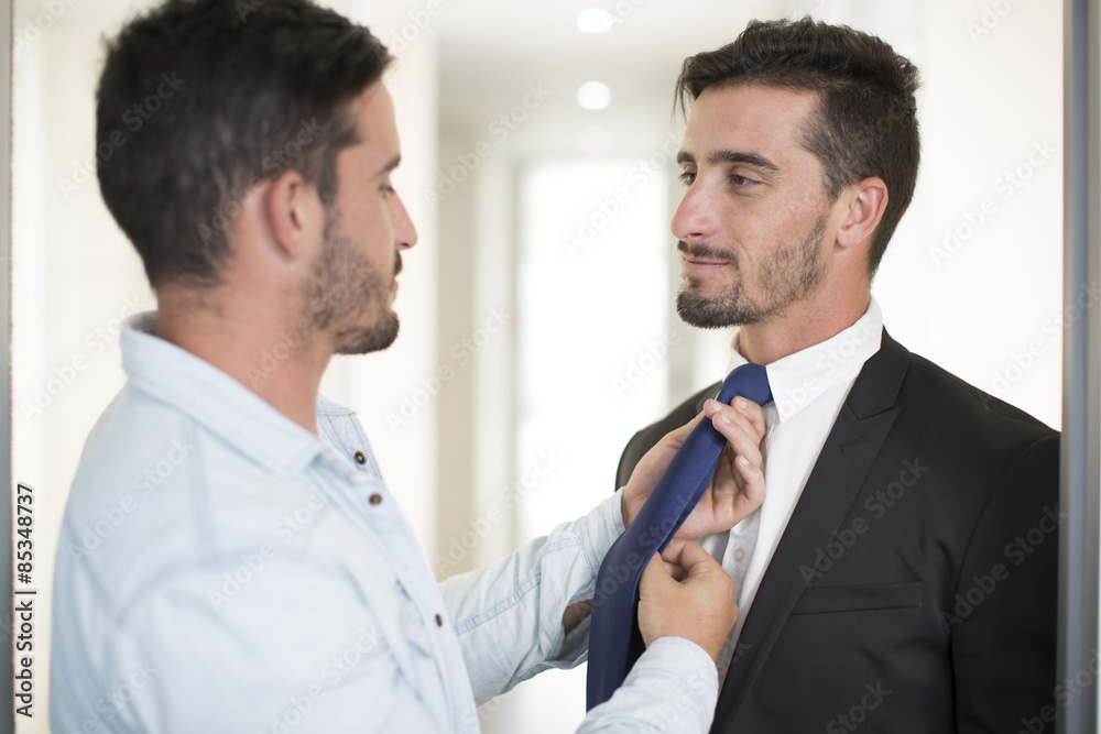 Casually dressed man adjusting tie of twin brother in office Casually dressed man adjusting tie of twin brother in office