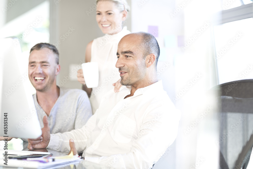 Three colleagues looking at screen in an office Three colleagues looking at screen in an office