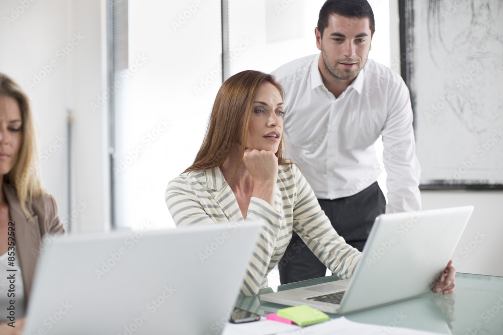 Businesswomen and businessman in office working on laptops Businesswomen and businessman in office working on laptops