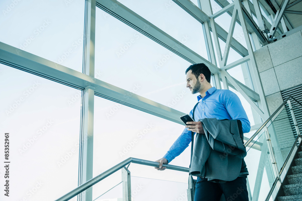 Young businessman with cell phone looking out of window Young businessman with cell phone looking out of window