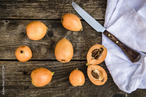 Sliced and whole medlars and a kitchen knife photo