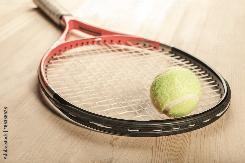 tennis ball lying on the racket on a wooden surface