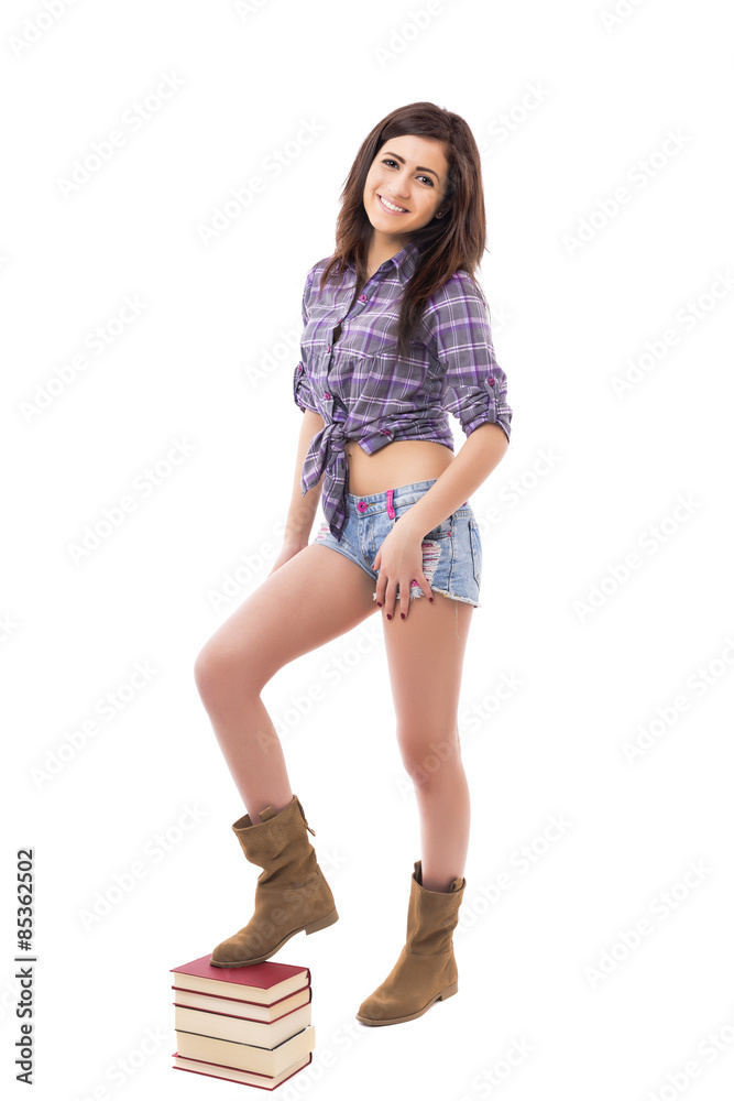 Studio shot of cute teenage girl standing on pile of books Studio shot of cute teenage girl standing on pile of books