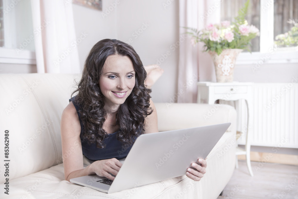 Portrait of smiling woman using laptop in living room Portrait of smiling woman using laptop in living room