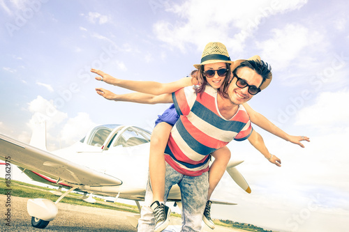 Happy hipster couple in love on airplane travel honeymoon