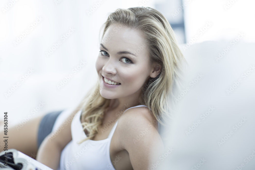 Portrait of blond woman lying on a couch with a magazine Portrait of blond woman lying on a couch with a magazine