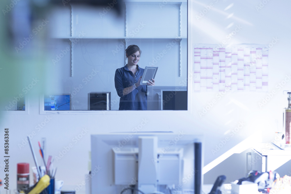 Young woman in factory office using digital tablet
