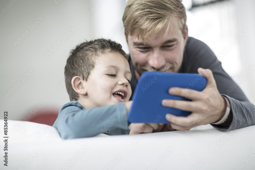 Father and little son on couch looking at a tablet Father and little son on couch looking at a tablet