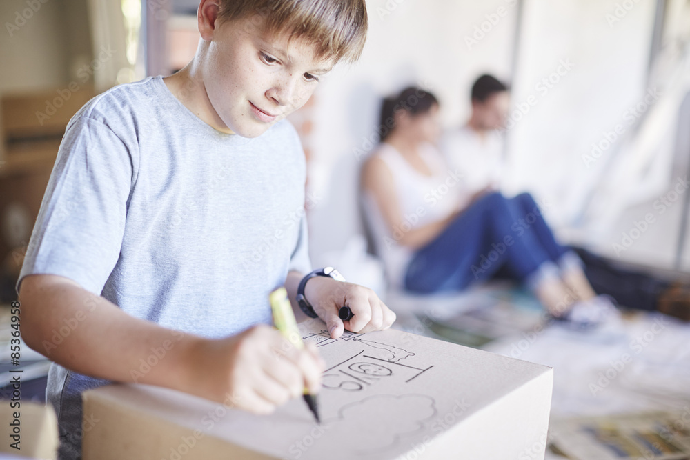 Family moving house, boy writing on a box Family moving house, boy writing on a box