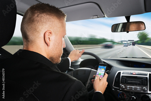 Businessman Using Cellphone While Driving A Car