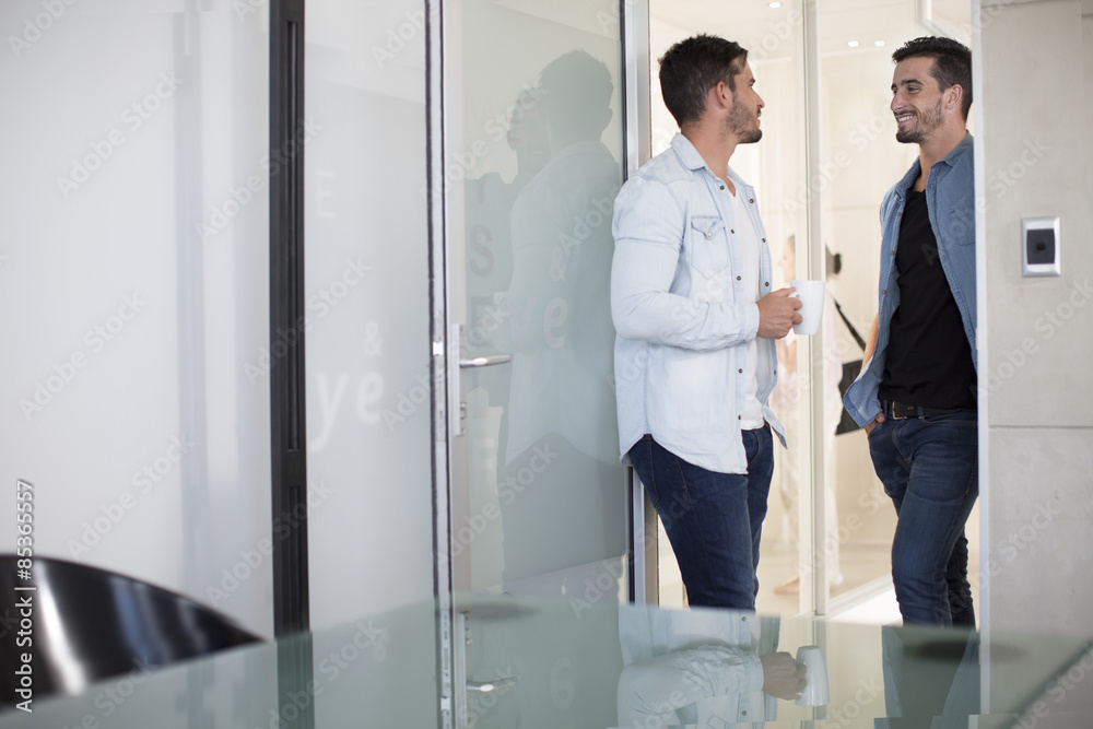 Two casually dressed twin males in office talking Two casually dressed twin males in office talking