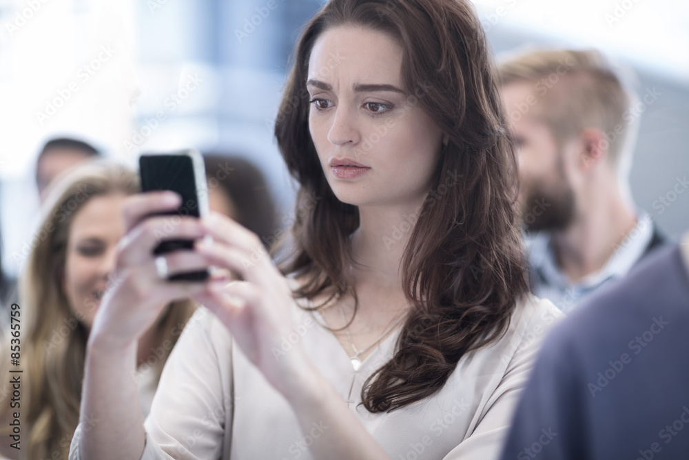 Annoyed woman looking on cell phone in busy city Annoyed woman looking on cell phone in busy city
