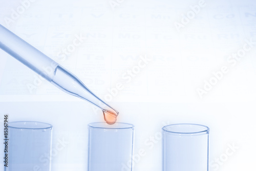 Laboratory pipette with drop of liquid over glass test tubes