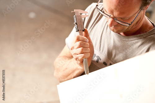 carpenter measuring a board with calipers